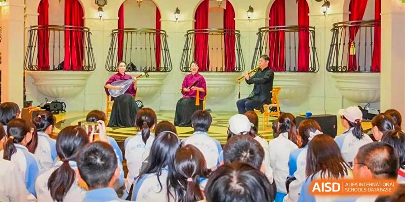 Students from the CNUH-GA Curriculum Partnership Program watching a duo perform music with traditional and modern instruments on a balcony stage.