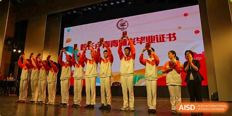 A group of male students from the CNUH-GA Curriculum Partnership Program holding up awards or trophies on stage during a ceremony.