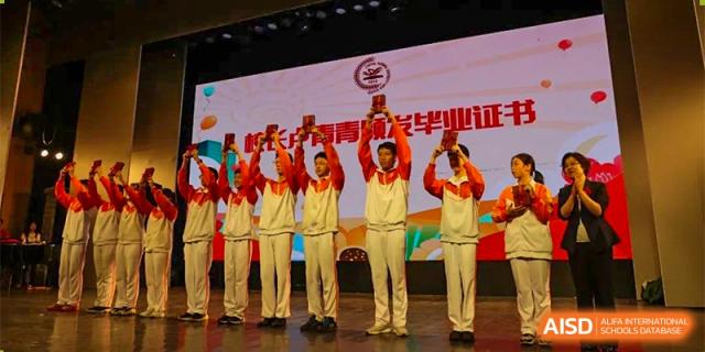 A group of male students from the CNUH-GA Curriculum Partnership Program holding up awards or trophies on stage during a ceremony.