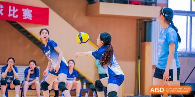 A female student from the CNUH-GA Curriculum Partnership Program setting a volleyball for a teammate during an indoor practice.