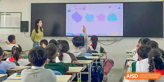 A Yancheng Foreign Language School classroom scene where a student is actively raising their hand to answer a question.