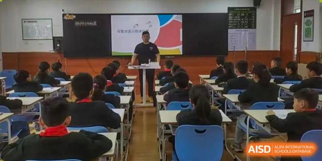 A teacher giving a presentation to Yancheng Foreign Language School students seated in a classroom setting.