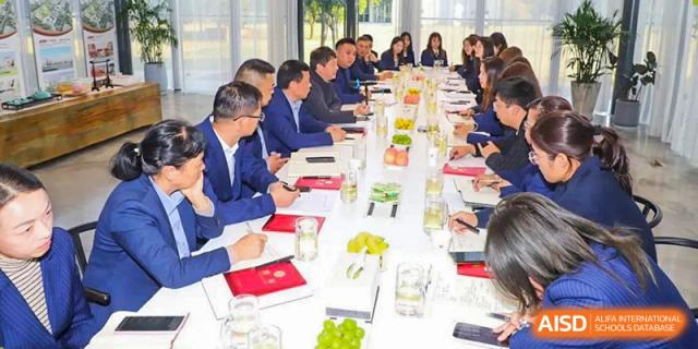 A formal meeting of several adults, possibly board members or dignitaries, seated around a long table at Yancheng Foreign Language School.