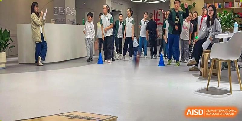 Students at Yancheng Foreign Language School participating in an indoor activity, standing in a line between two blue cones.