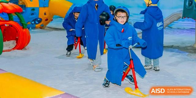 A group of Yancheng Foreign Language School students in blue snowsuits and helmets participating in an ice or snow activity, possibly sliding or snow tubing.