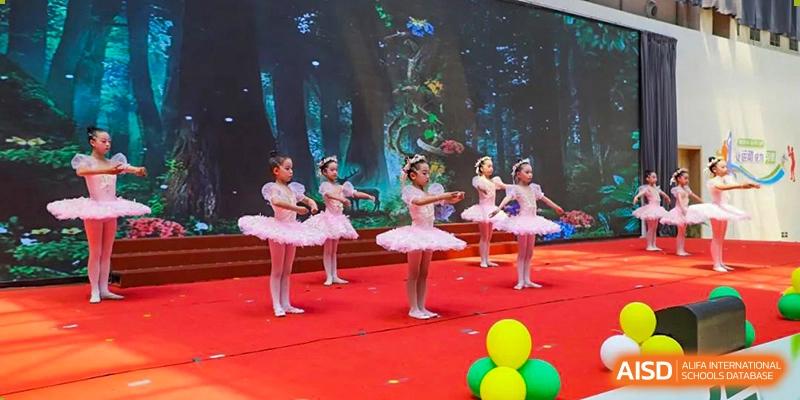 A group of young Yancheng Foreign Language School students performing a ballet dance on a brightly lit stage.