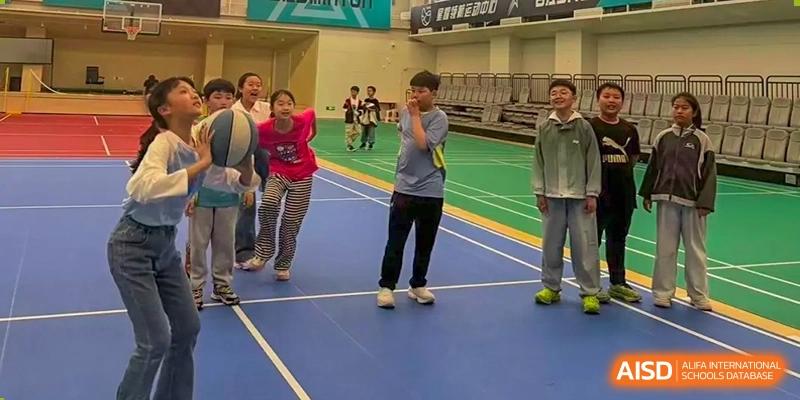 Two Yancheng Foreign Language School students participating in an indoor physical activity or game on a blue sports court.