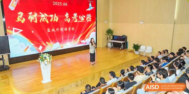A speaker or teacher from Yancheng Foreign Language School addressing students in an auditorium or lecture hall.