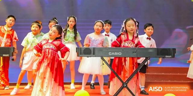 Young Yancheng Foreign Language School students performing music and singing on stage, with one student playing a Casio keyboard.