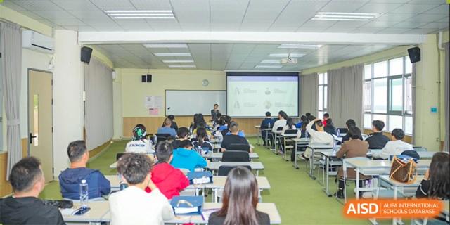 Students seated in a large lecture hall or classroom, facing a projector screen and an instructor, Fuyuan British American School.