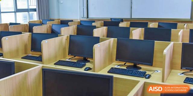 Rows of computer workstations with monitors in a dedicated computer lab or classroom, Fuyuan British American School.
