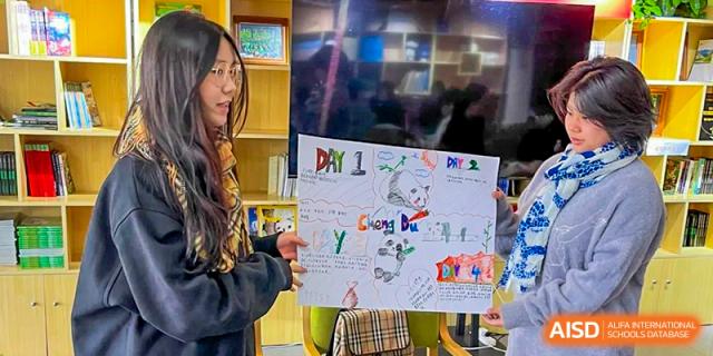 A student holding up a colorful, hand-drawn project poster that includes text and drawings, Fuyuan British American School.