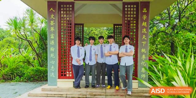 A group of five male students in school uniforms posing together in front of a traditional Chinese-style red pavilion, Fuyuan British American School.