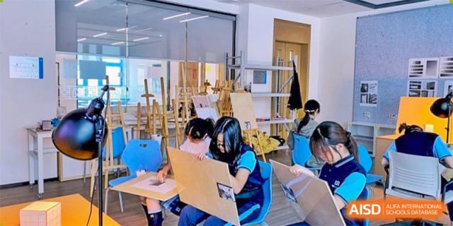 Students drawing or painting in a brightly lit art studio with easels and art supplies at ISA Wuhan International School.