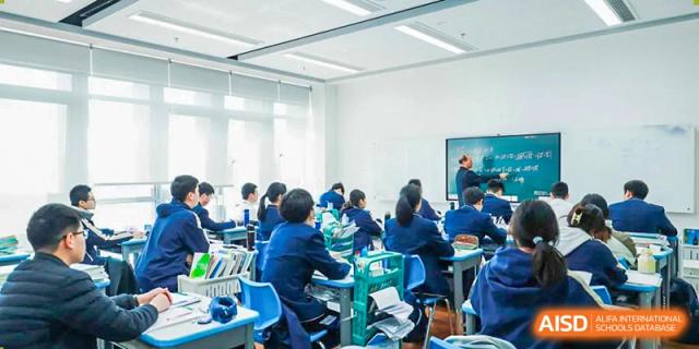 Students in blue uniforms actively engaged in a lively classroom discussion or activity at ISA Wuhan International School.