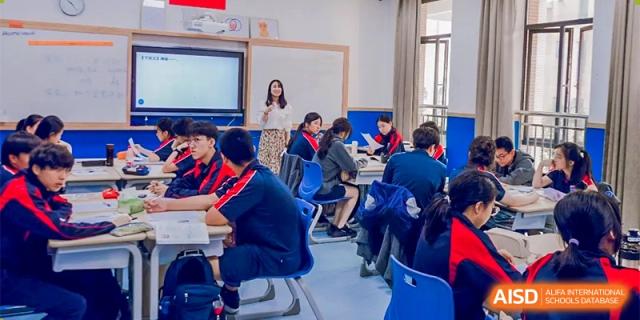Students from Changwai Bilingual School seated at desks, listening to a teacher in a classroom.