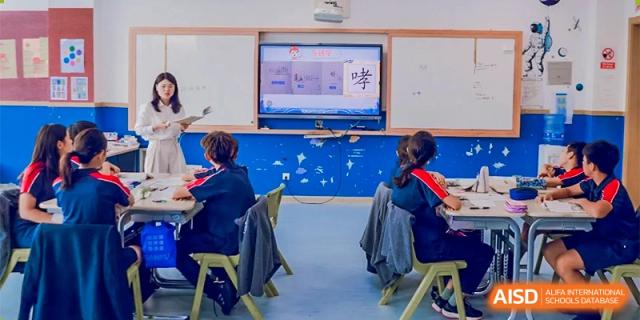 Students from Changwai Bilingual School are in a classroom, watching a presentation on a screen.
