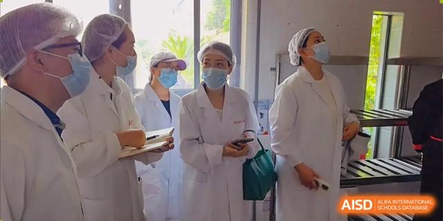 Students from Changwai Bilingual School in white lab coats, participating in a science activity.