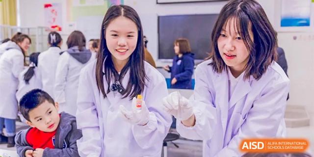 A smiling student from Changwai Bilingual School wearing a lab coat.