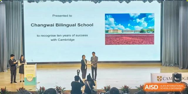 A teacher or staff member from Changwai Bilingual School receiving an award on stage during a school event.