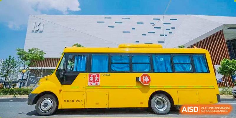 A bright yellow school bus parked outside a modern building at ISA Wuhan International School.