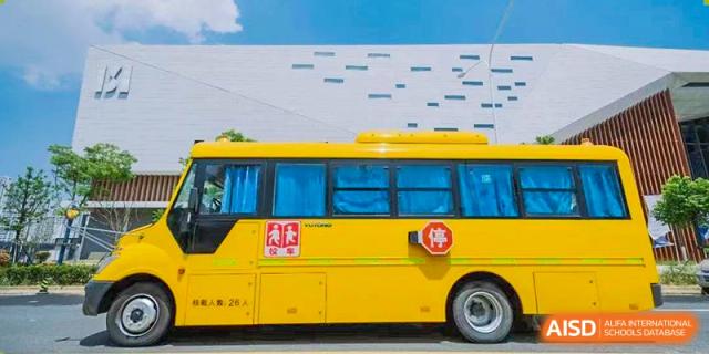A bright yellow school bus parked outside a modern building at ISA Wuhan International School.