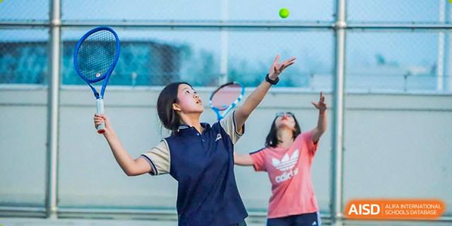 Two students playing a racket sport, either badminton or tennis, outdoors at ISA Wuhan International School.