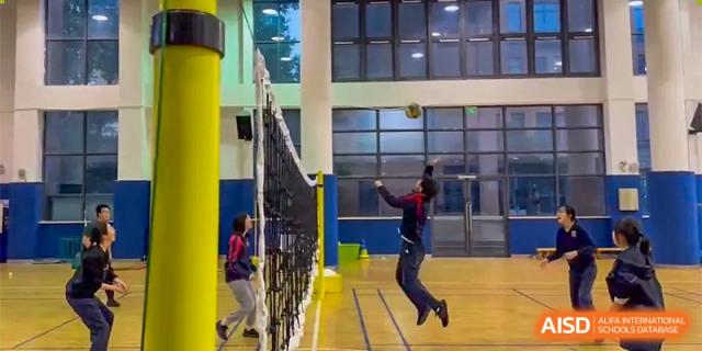 Students from Changwai Bilingual School playing a volleyball game indoors.