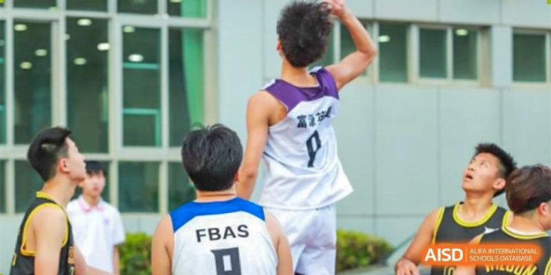 A basketball player from Fuyuan British American School in a purple and white jersey preparing to shoot or pass the ball during a game.