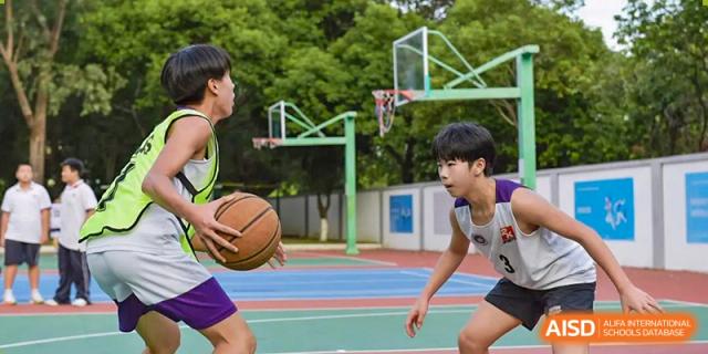 Students from the Fuyuan British American School basketball team playing a game on an outdoor court.