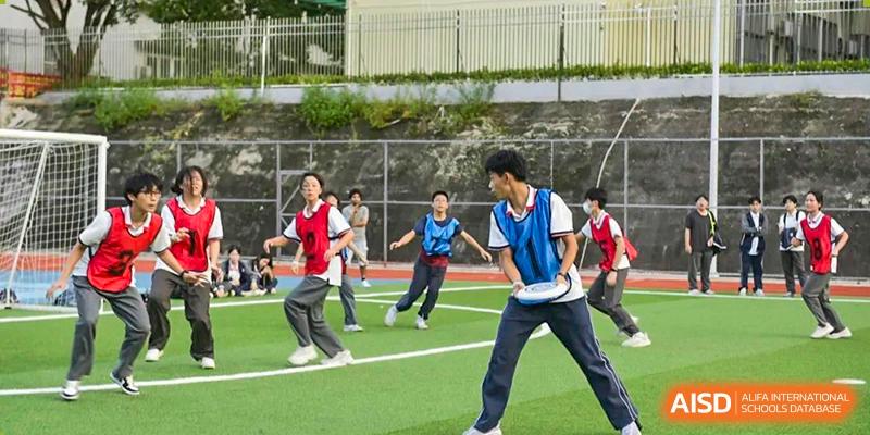 Students from Fuyuan British American School running and playing a game of soccer or field sport outdoors.
