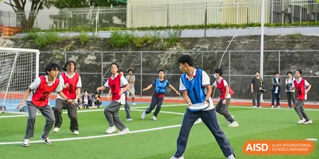 Students from Fuyuan British American School running and playing a game of soccer or field sport outdoors.