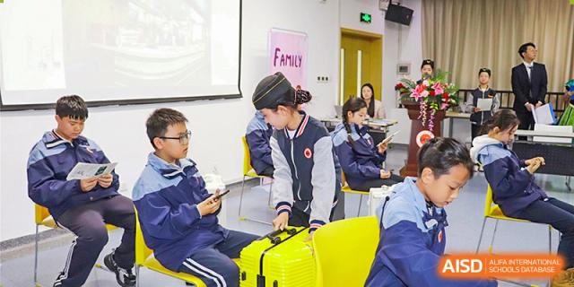 A female student working on a project with a bright yellow suitcase nearby in a classroom at Glocal Elite International School.