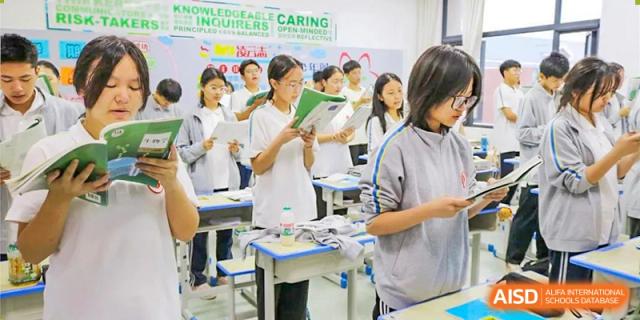 Students reading books or materials at their desks in a busy, active classroom setting at Glocal Elite International School.