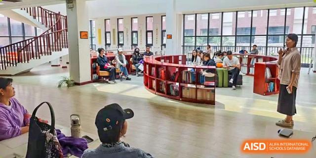 Students and a teacher sitting in a circular discussion group surrounded by low bookshelves in the modern library at Glocal Elite International School.