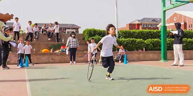 A student running and playing a game with two large hoops on an outdoor sports court at Glocal Elite International School.