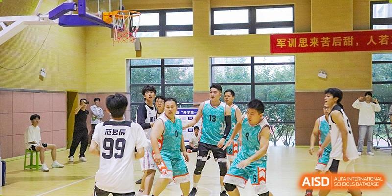 Students playing an intense game of indoor basketball, with one player dribbling past defenders in turquoise jerseys at Glocal Elite International School.