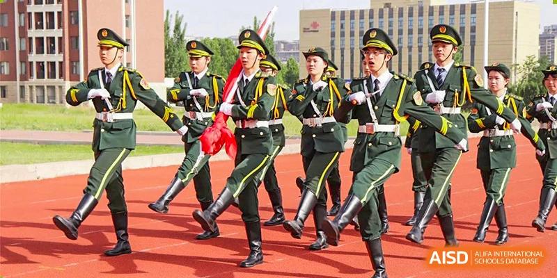 Students in military-style uniforms marching in formation on a track during a school ceremony at Glocal Elite International School.
