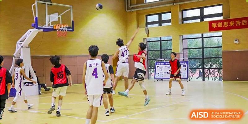 Two students jumping for a rebound during a lively basketball game on an indoor court at Glocal Elite International School.