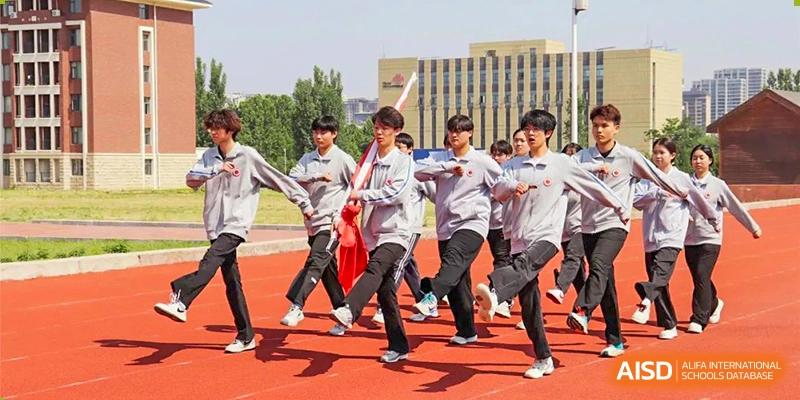 Students participating in an outdoor performance or group activity on a running track, with some holding jackets as props, at Glocal Elite International School.