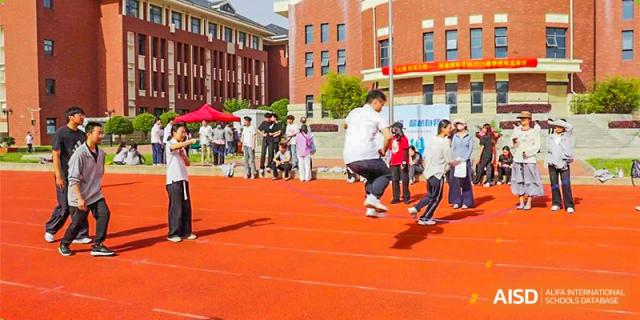 A student performing a long jump or high jump during a track and field event on a sunny day at Glocal Elite International School.