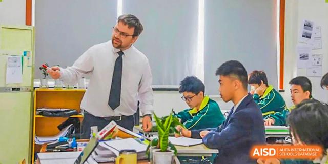 A foreign teacher in a tie instructing students during a science lesson in a laboratory setting at Maple Leaf International School-Zhenjiang.