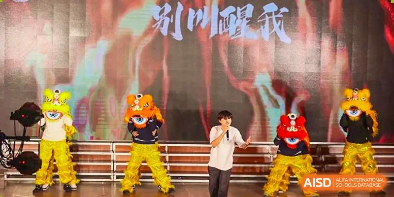 A young student singing on stage next to a person in an orange tiger mascot costume at Maple Leaf International School-Zhenjiang.
