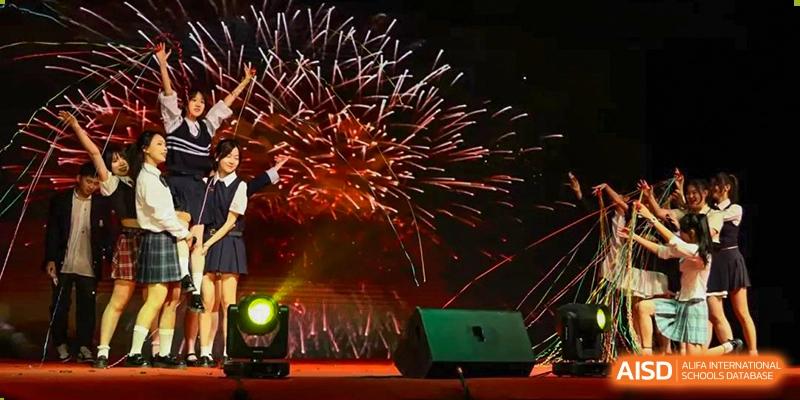 Fireworks exploding over a stage with a bright spotlight during an evening event or celebration at Maple Leaf International School-Zhenjiang.
