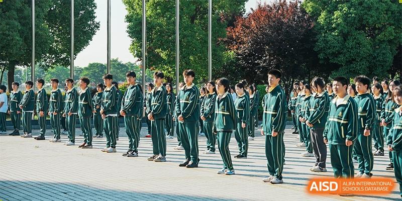 A group of students in green military-style uniforms standing in formation outdoors at Maple Leaf International School-Zhenjiang.