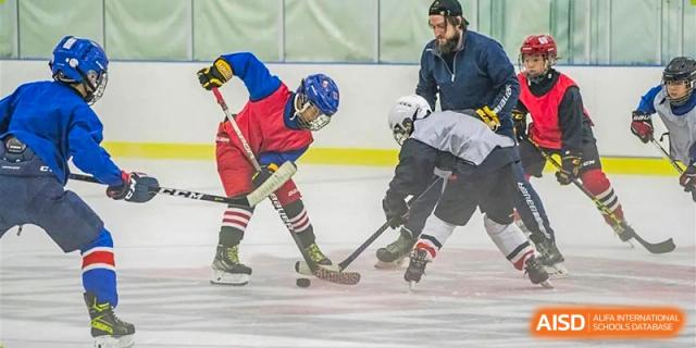 Two people playing ice hockey, one checking the puck, on an ice rink at Maple Leaf International School-Zhenjiang.