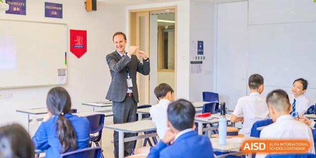 A teacher at Harrow LiDe School Hengqin gestures while instructing a group of primary students in a classroom.