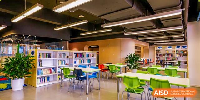 Interior view of the colorful, modern learning space or library area at Harrow LiDe School Hengqin with various tables and chairs.