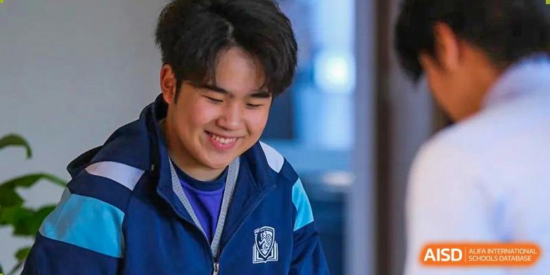 Close-up portrait of a smiling male student at Harrow LiDe School Hengqin wearing a navy blue and light blue school jacket.