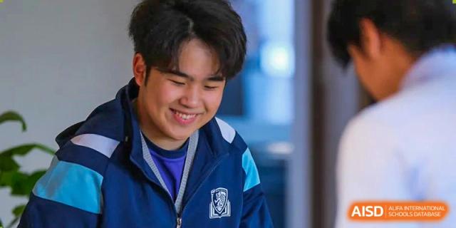 Close-up portrait of a smiling male student at Harrow LiDe School Hengqin wearing a navy blue and light blue school jacket.